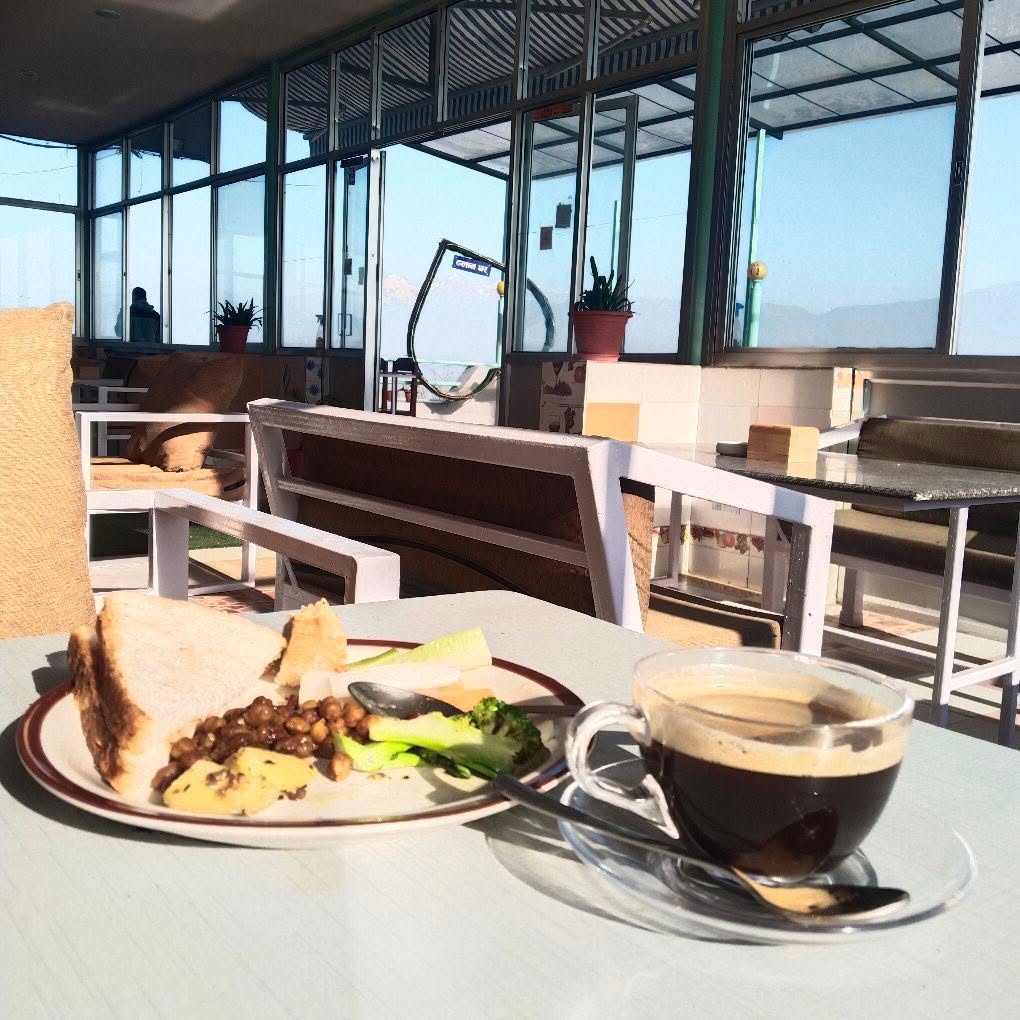 Breakfast plate and coffee on the terrace table, mountains in the background