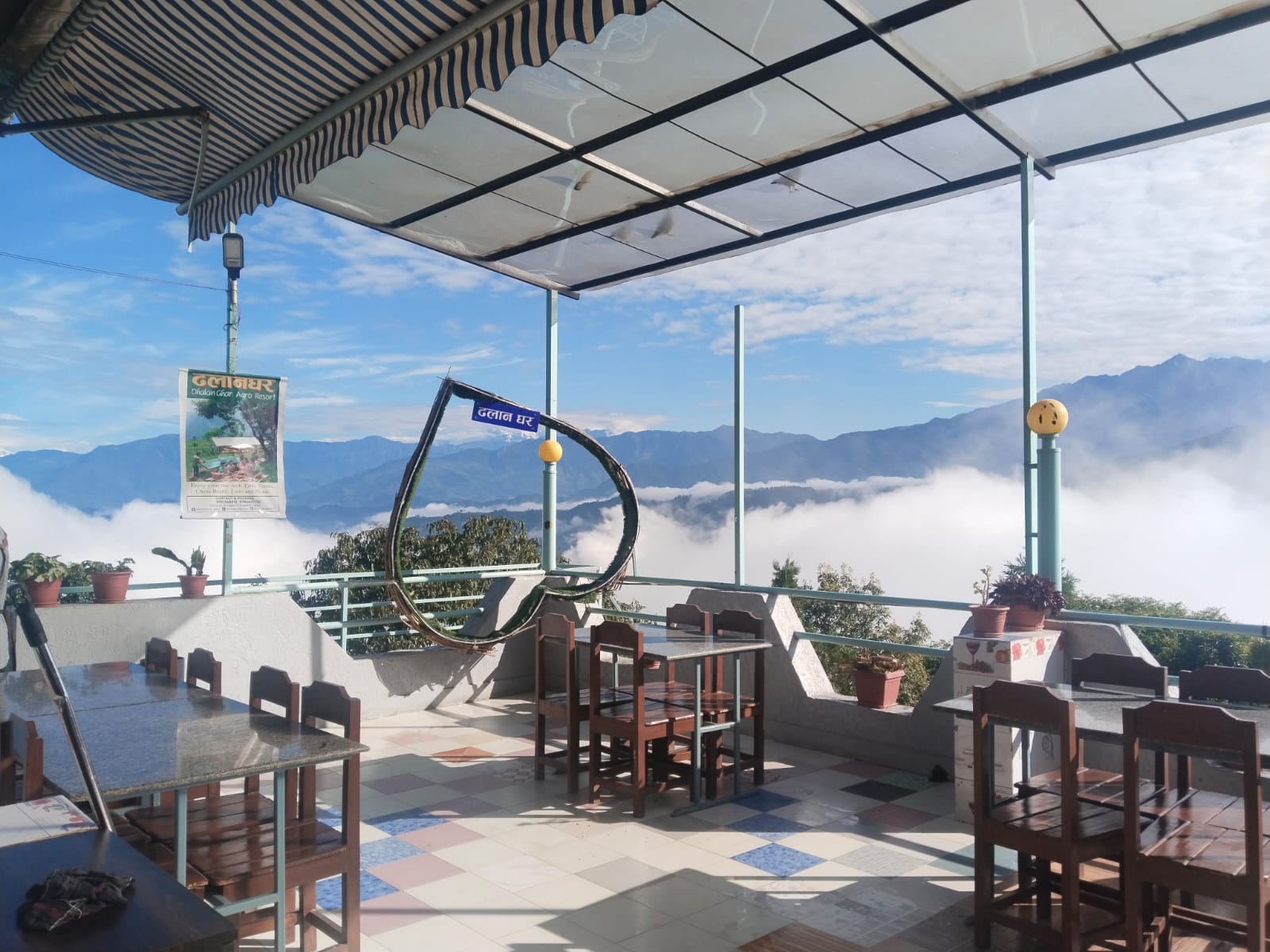 Rooftop terrace of Dhalan Ghar with wooden chairs, overlooking mountains and a sea of clouds